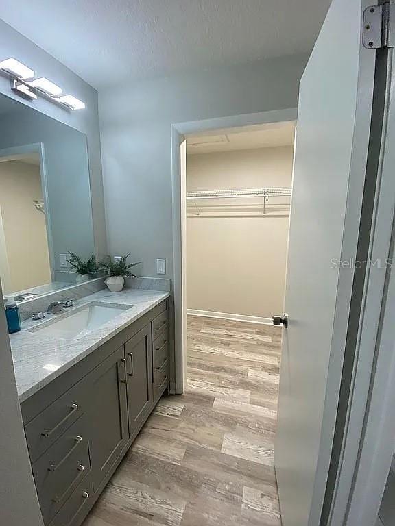 bathroom with vanity, wood finished floors, a spacious closet, and a textured ceiling