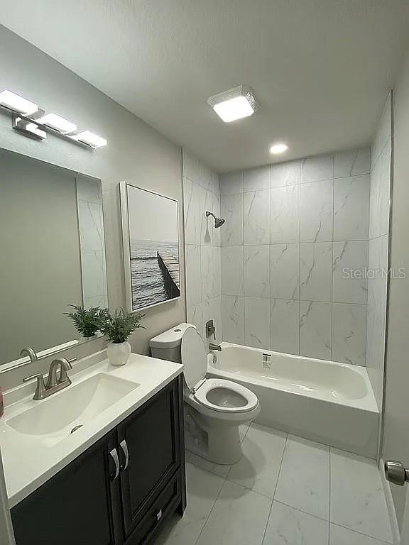 full bathroom with shower / bathing tub combination, toilet, marble finish floor, and vanity