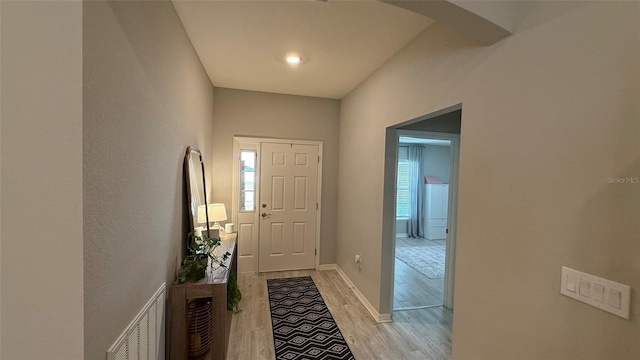 doorway featuring light wood finished floors, visible vents, baseboards, and a wealth of natural light