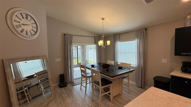 dining room with visible vents, an inviting chandelier, light wood-type flooring, and lofted ceiling