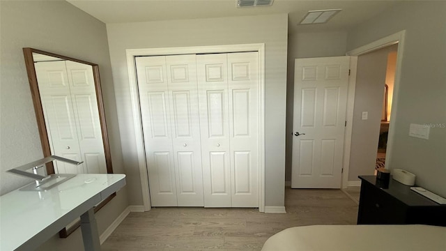 bedroom with visible vents, baseboards, light wood-style floors, and a closet