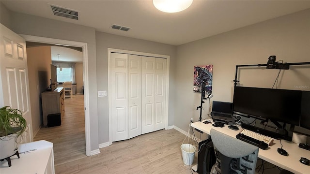 office area with baseboards, visible vents, and light wood-type flooring