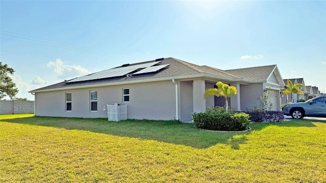 view of side of property with a lawn, an attached garage, solar panels, and stucco siding