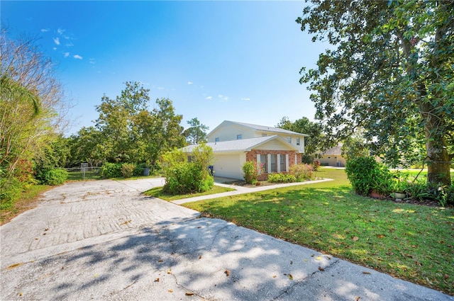 view of front of property with concrete driveway, an attached garage, brick siding, and a front yard