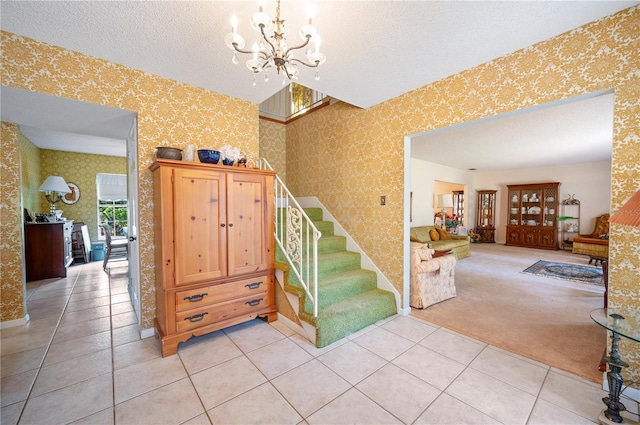 staircase featuring tile patterned flooring, wallpapered walls, a chandelier, carpet flooring, and a textured ceiling