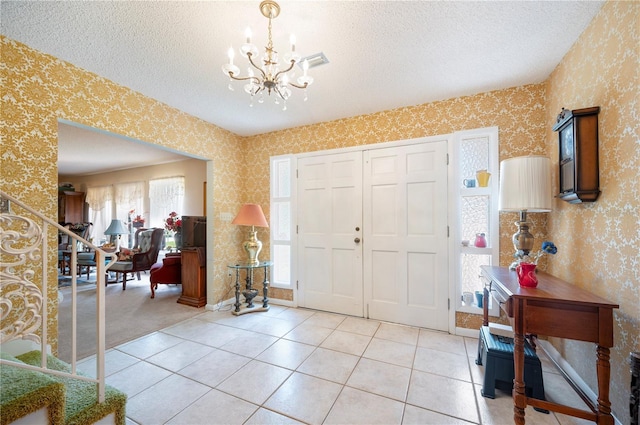 entryway with a chandelier, a textured ceiling, wallpapered walls, and a wealth of natural light