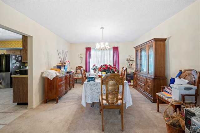 dining area featuring a textured ceiling, an inviting chandelier, light tile patterned floors, baseboards, and light colored carpet