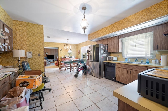 kitchen with wallpapered walls, a sink, hanging light fixtures, light countertops, and dishwasher