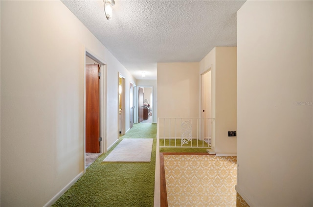 hall featuring carpet flooring, a textured ceiling, and baseboards