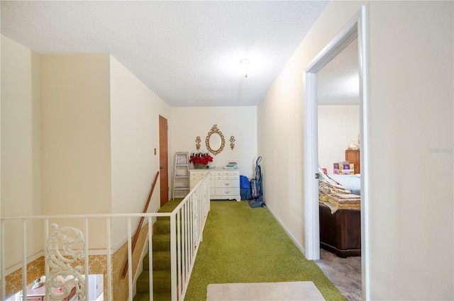 corridor with an upstairs landing, carpet, and a textured ceiling