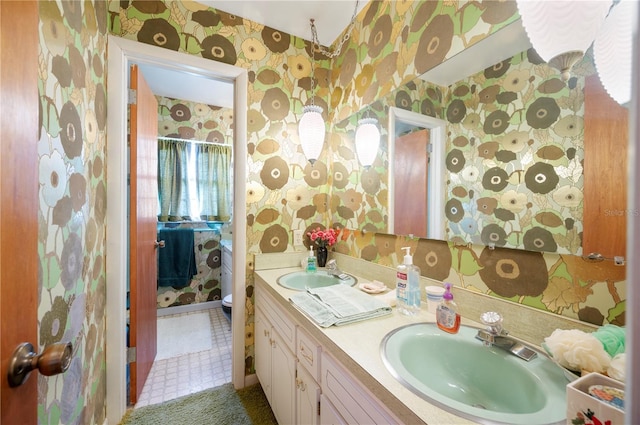 bathroom with a sink, double vanity, and wallpapered walls