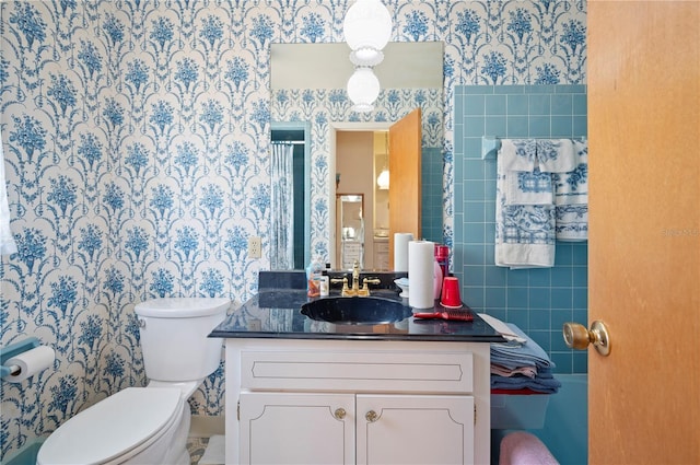 bathroom featuring toilet, vanity, and wallpapered walls