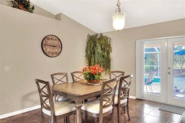 dining area with french doors, lofted ceiling, baseboards, and dark tile patterned floors