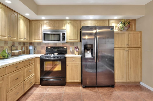 kitchen featuring tasteful backsplash, light brown cabinets, stainless steel appliances, and tile counters