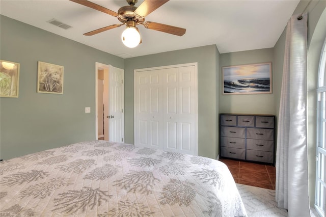 tiled bedroom with a closet, visible vents, and ceiling fan