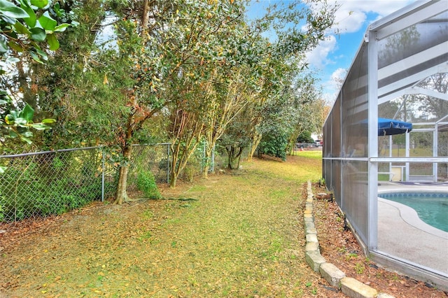 view of yard featuring an outdoor pool, a lanai, and fence