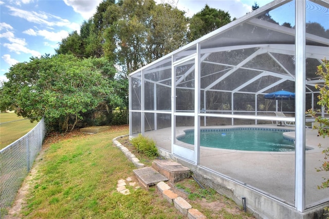 view of swimming pool with a fenced in pool, fence, glass enclosure, a yard, and a patio area