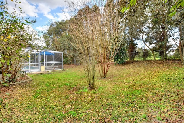 view of yard featuring a lanai, an outdoor pool, and fence