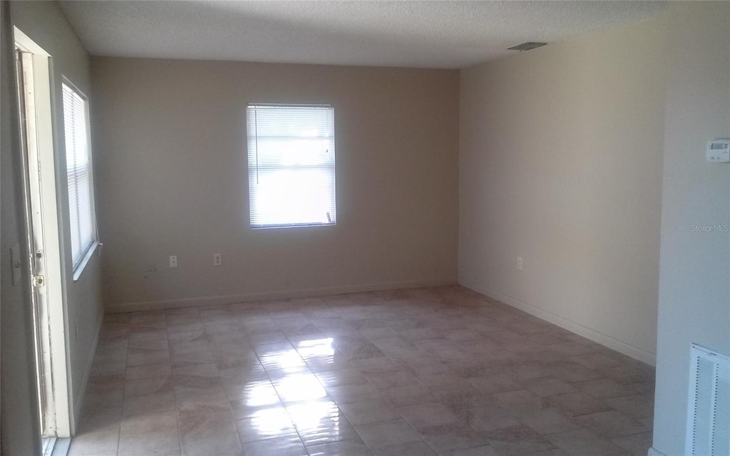 empty room with baseboards, visible vents, and a wealth of natural light