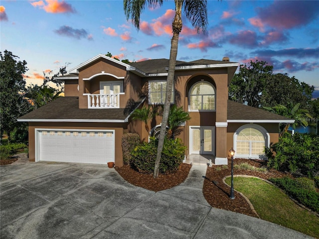 view of front of property with stucco siding, french doors, driveway, and a balcony