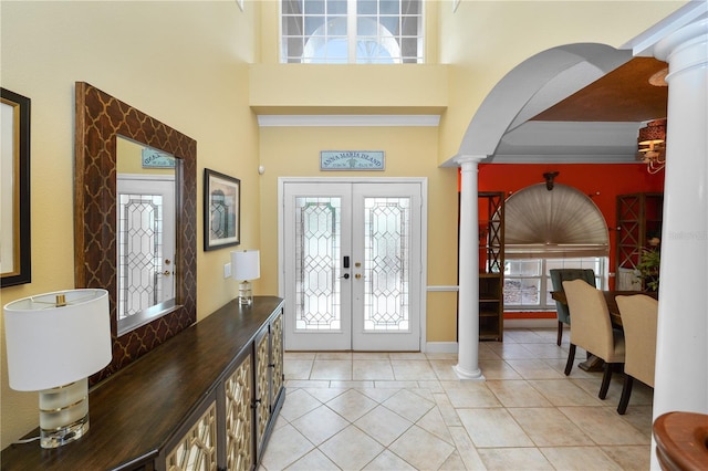 entrance foyer featuring a high ceiling, light tile patterned flooring, french doors, and ornate columns