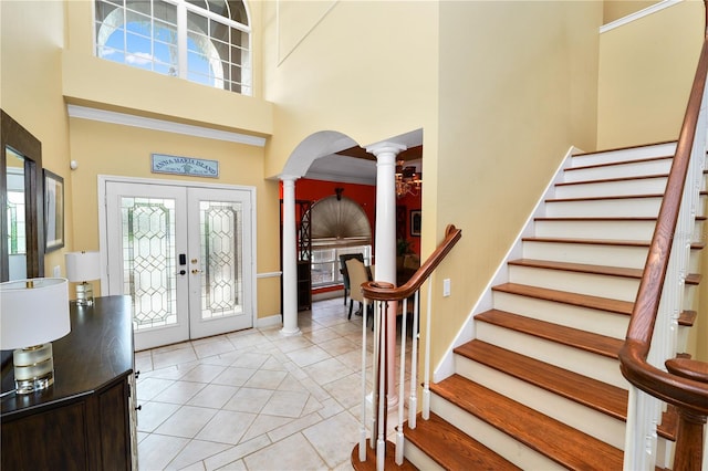 entryway with decorative columns, french doors, a towering ceiling, and a healthy amount of sunlight