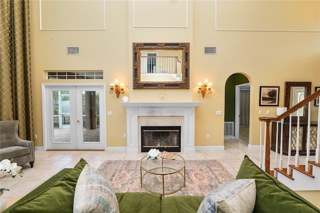 living area featuring visible vents, arched walkways, a high ceiling, tile patterned flooring, and stairs