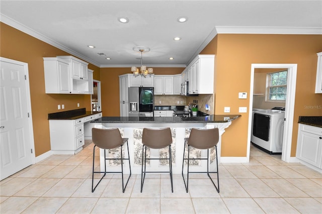 kitchen featuring washer and dryer, an inviting chandelier, light tile patterned flooring, and appliances with stainless steel finishes