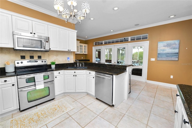 kitchen featuring a sink, stainless steel appliances, a peninsula, crown molding, and a chandelier