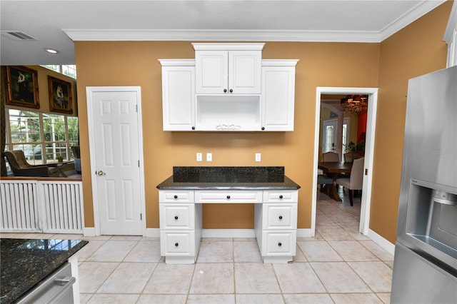 kitchen featuring visible vents, stainless steel fridge, crown molding, and dark stone countertops