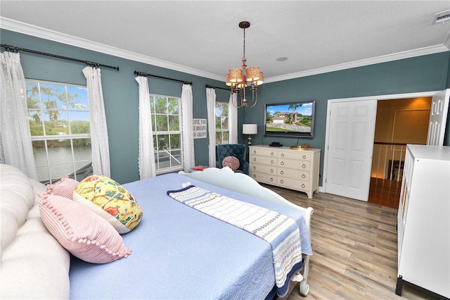 bedroom featuring a notable chandelier, ornamental molding, visible vents, and wood finished floors