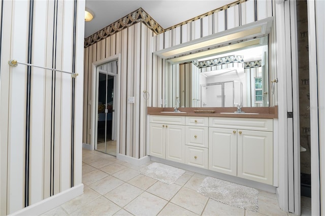 full bathroom featuring tile patterned floors, double vanity, wallpapered walls, and a sink