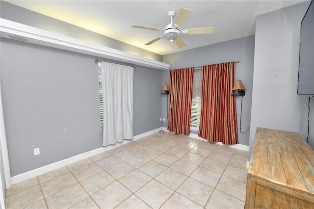 spare room featuring baseboards, light tile patterned flooring, and a ceiling fan