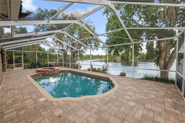 view of swimming pool with glass enclosure, a water view, a pool with connected hot tub, and a patio area