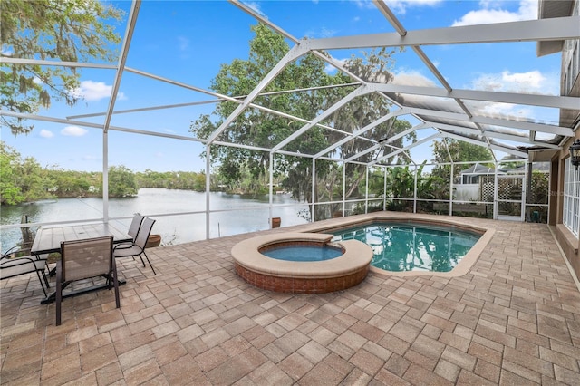 view of swimming pool with glass enclosure, a water view, a pool with connected hot tub, and a patio area