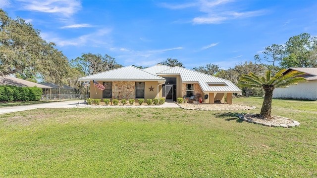 view of front of house with metal roof, stone siding, a front yard, and a standing seam roof