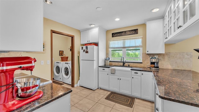 kitchen with glass insert cabinets, washer and clothes dryer, decorative backsplash, freestanding refrigerator, and white cabinetry