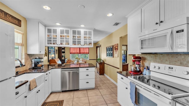 kitchen with white appliances, visible vents, light tile patterned flooring, white cabinetry, and backsplash