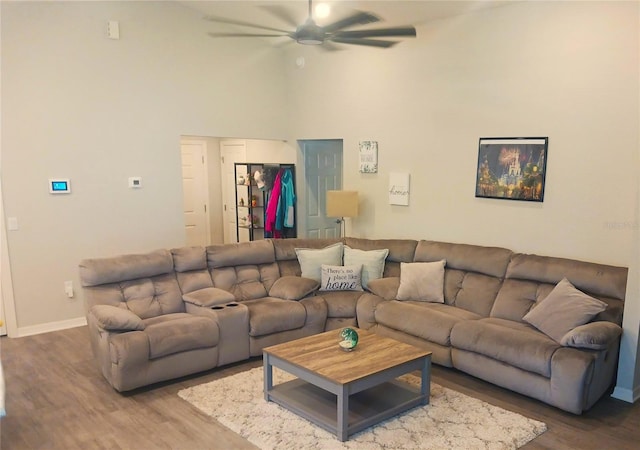 living area with baseboards, ceiling fan, and wood finished floors