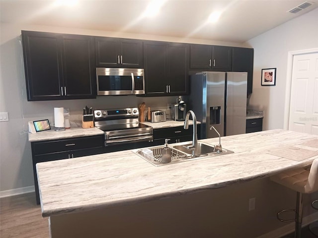 kitchen featuring visible vents, appliances with stainless steel finishes, dark cabinetry, and vaulted ceiling