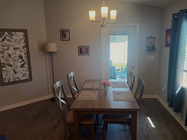 dining space with dark wood-type flooring, baseboards, and a chandelier