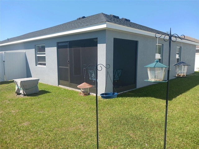 back of house featuring a yard, fence, roof with shingles, and stucco siding