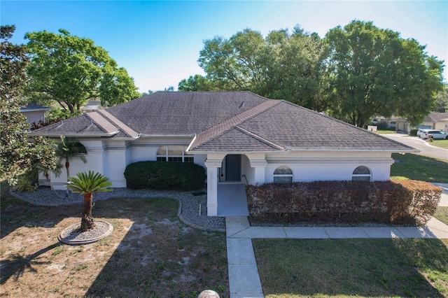 single story home with stucco siding, a shingled roof, and a front lawn