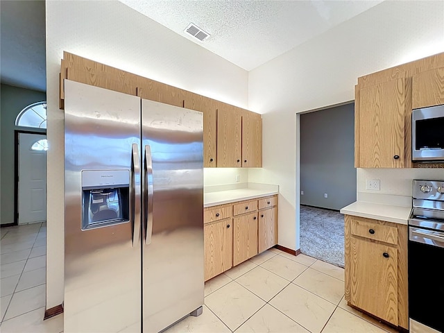 kitchen featuring visible vents, light brown cabinets, a textured ceiling, stainless steel appliances, and light countertops