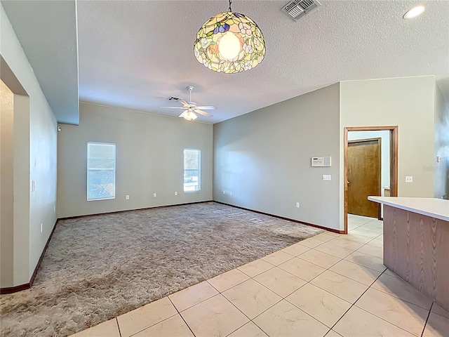 interior space featuring a ceiling fan, baseboards, visible vents, a textured ceiling, and light carpet