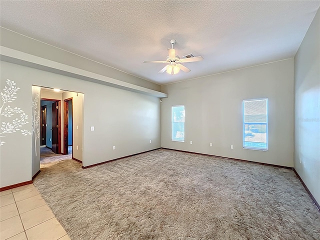 spare room featuring a textured ceiling, a ceiling fan, visible vents, baseboards, and light carpet