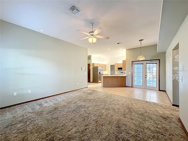 unfurnished living room featuring visible vents, a ceiling fan, french doors, lofted ceiling, and light colored carpet