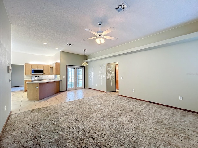 unfurnished living room featuring a ceiling fan, visible vents, french doors, a textured ceiling, and light colored carpet