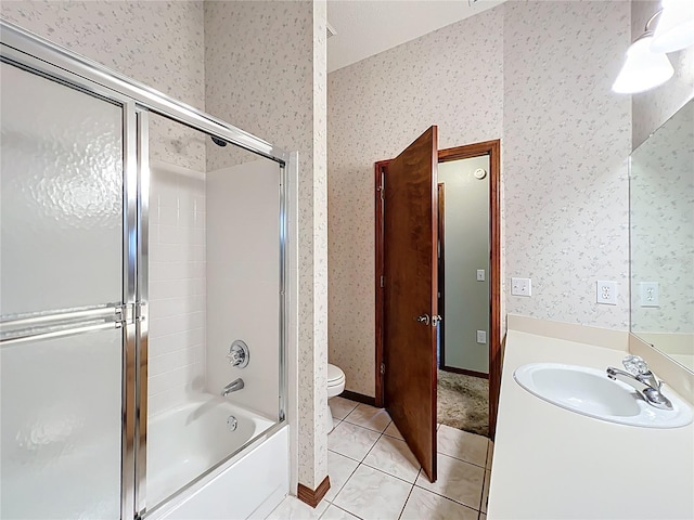 full bath featuring vanity, wallpapered walls, bath / shower combo with glass door, tile patterned floors, and toilet