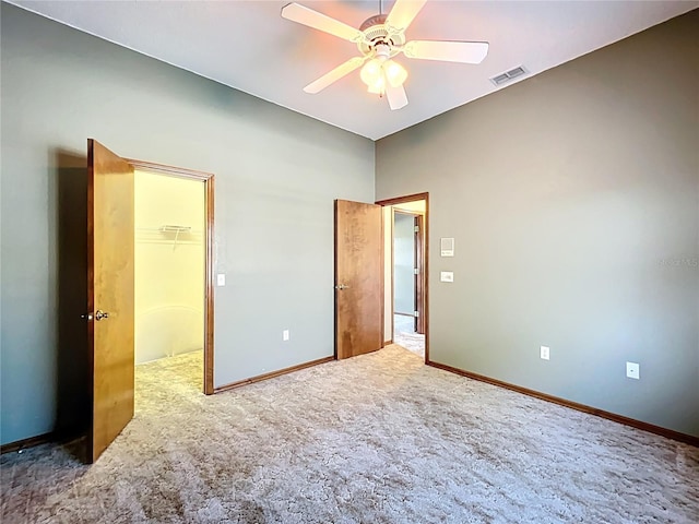 unfurnished bedroom featuring visible vents, carpet flooring, baseboards, ceiling fan, and a spacious closet